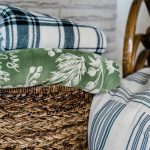 A wicker basket filled with various soft blankets and textiles, perfect for home comfort.