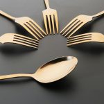 Stylish gold forks and spoon displayed on a black background for a sophisticated look.