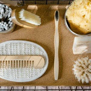 Top view of eco-friendly bath essentials including soap, sponge, and toothbrush on a tray.